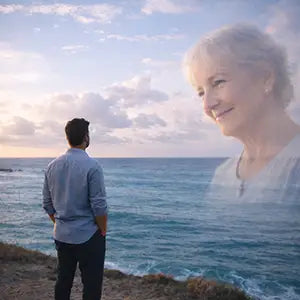 Photo edit showing a son by the ocean with his deceased mother softly overlaid in the sky.